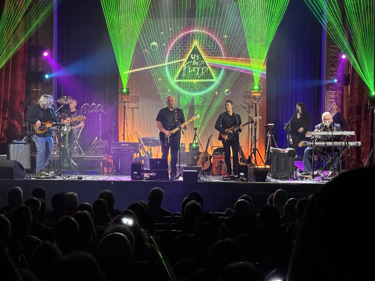 Us And Floyd performing live in a theater with lasers